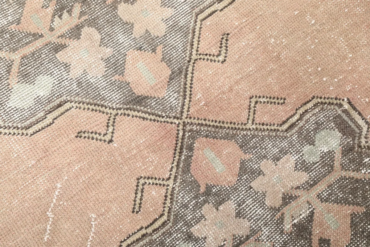 Close-up detail of the hand-knotted wool pile, showing color variations within the charcoal and rose areas