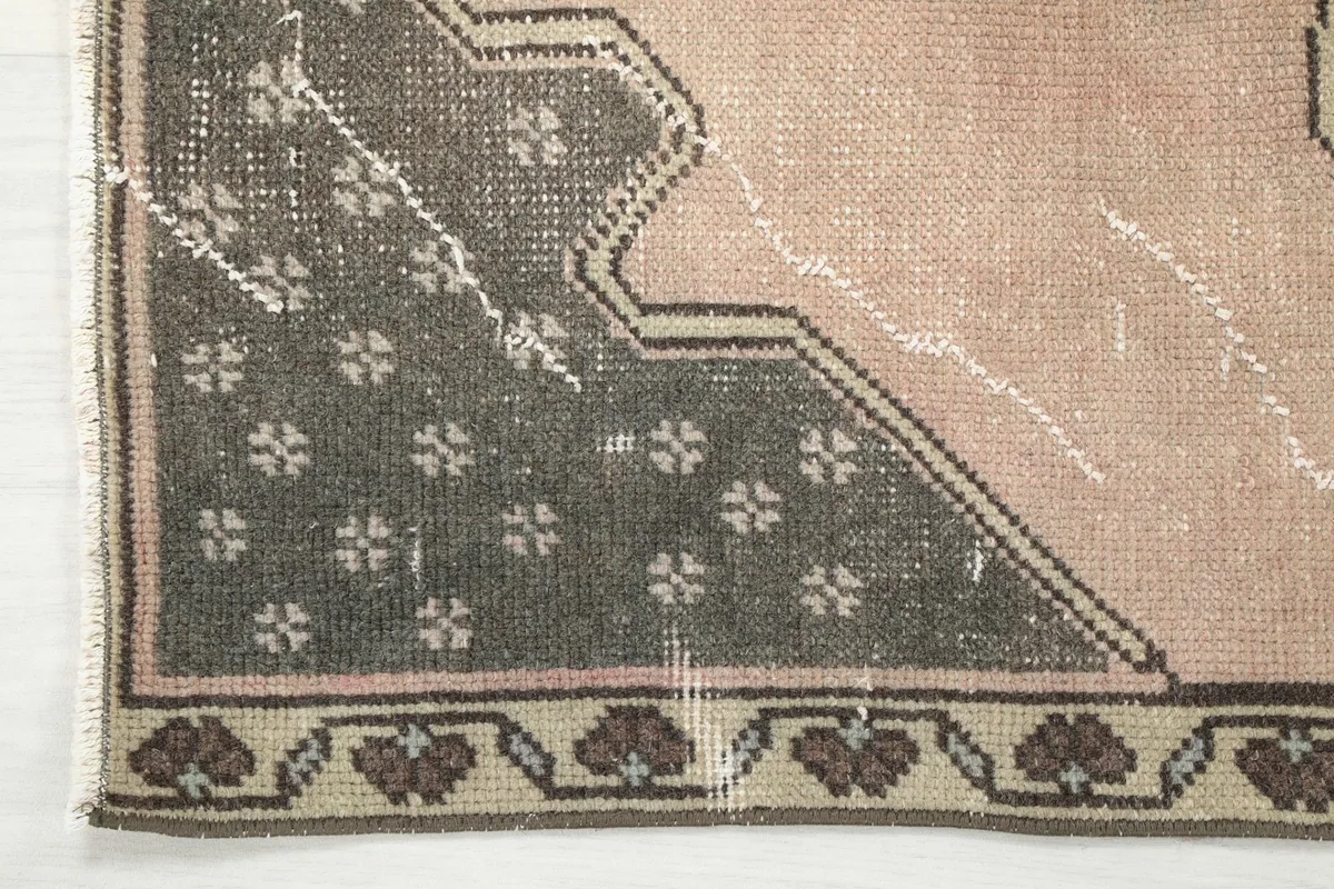 Corner detail of the runner rug, showing the charcoal border design and the rose field with slight wear