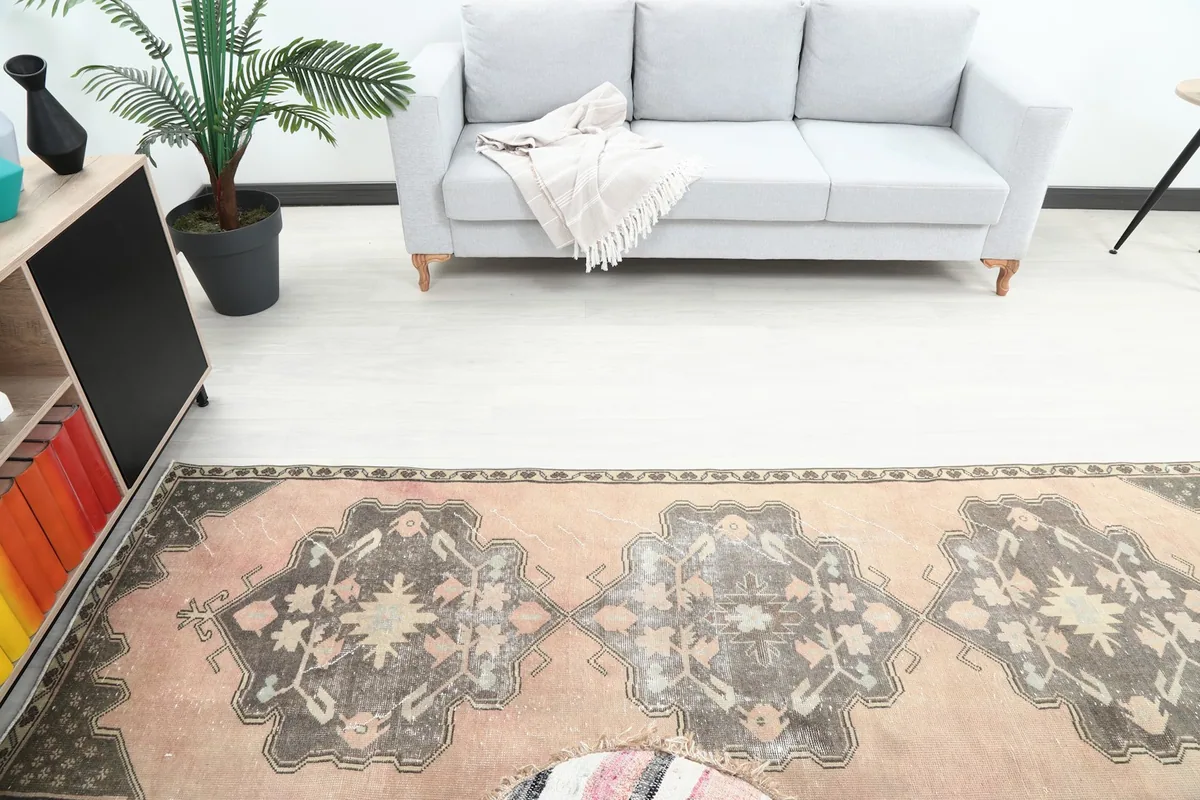 Overhead view of the runner rug in a room, capturing the repeating charcoal medallions on a rose background