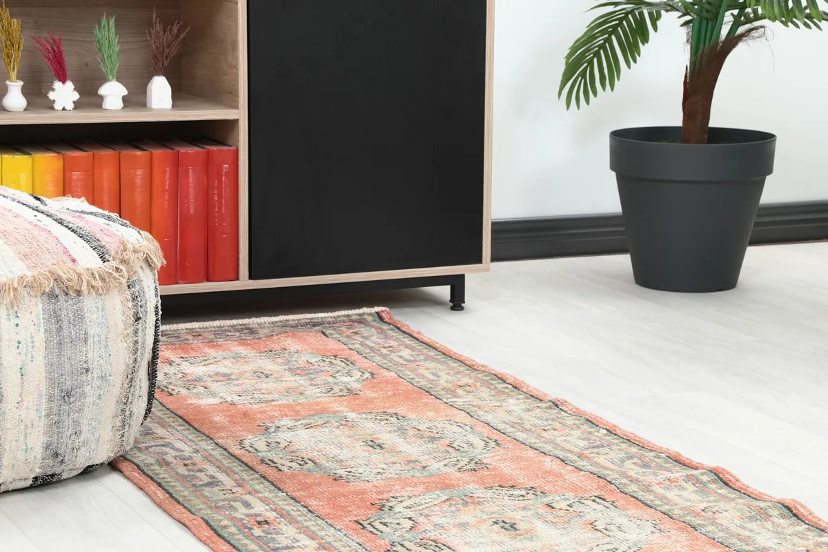Close-up view of the runner rug's end in a room setting, next to an ottoman and cabinet