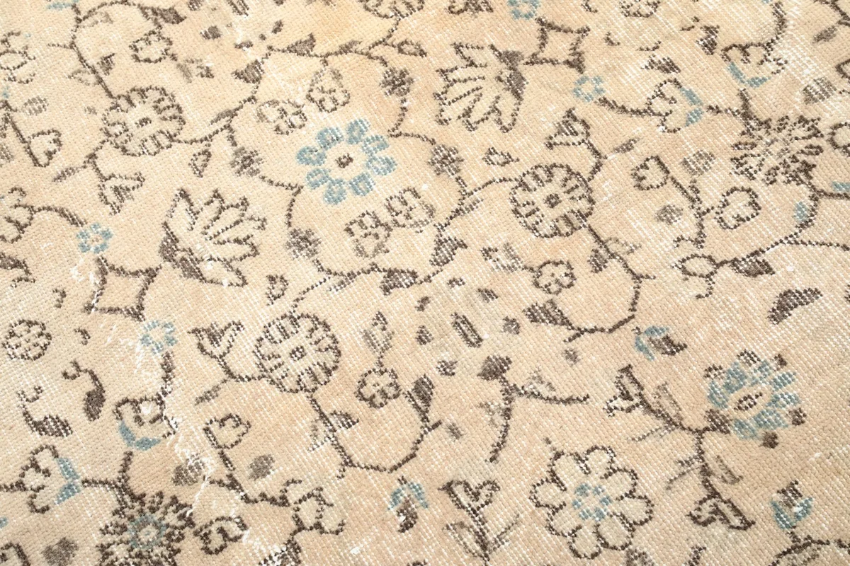 Close-up of the low wool pile and intricate hand-knotted floral design with visible wear.