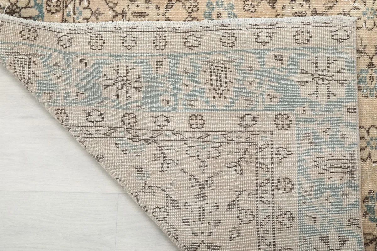 Close-up of the rug's reverse side, showing the knotting and the blue border's pattern from underneath.