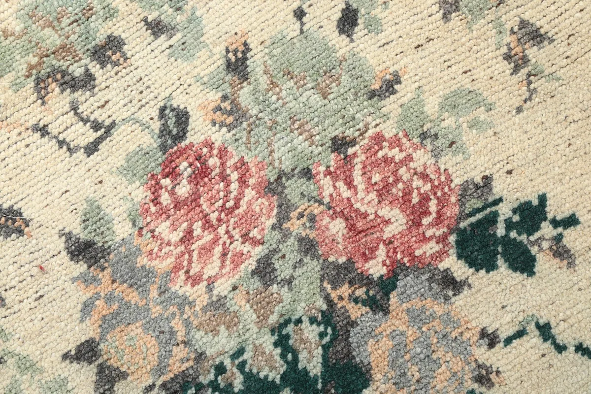Extreme close-up of the rug pile, focusing on the rose floral pattern and weave.