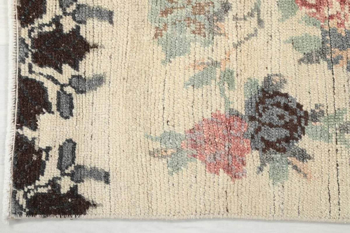 Detail of the rug's end, showing the dark brown border pattern and the ivory field.