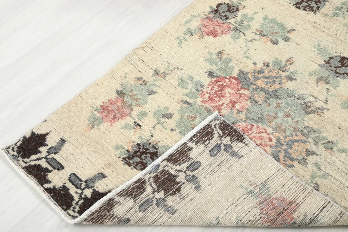 Corner of the rug folded back, showing the wool pile and cotton foundation.