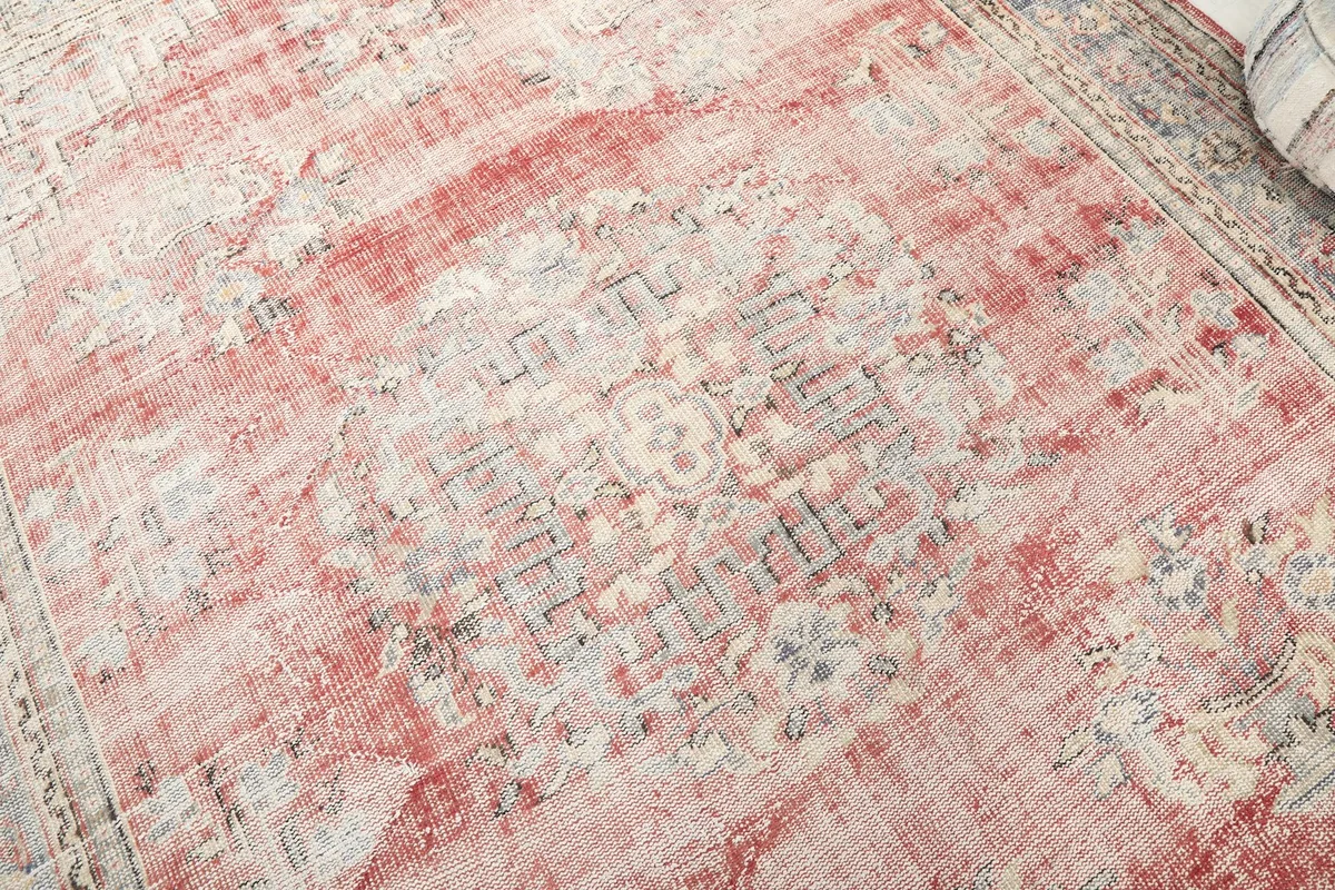 Close-up showing the central medallion motif and distressed rose and gray wool pile