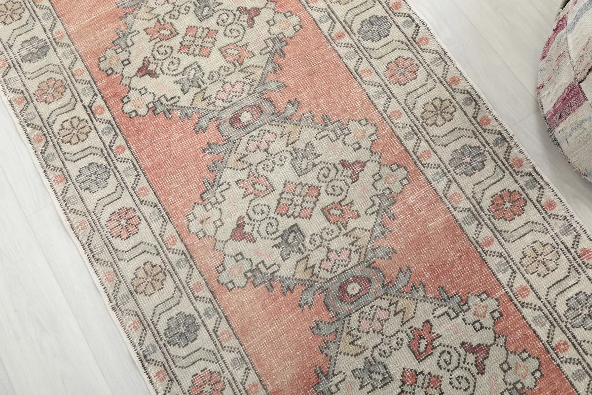 Detailed view of the central geometric motifs and the faded orange field of the runner rug.