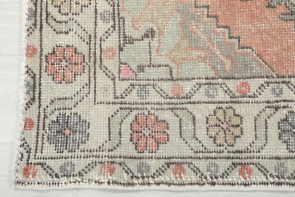 Detail of the border design with small floral elements and the fringe along the rug's edge.