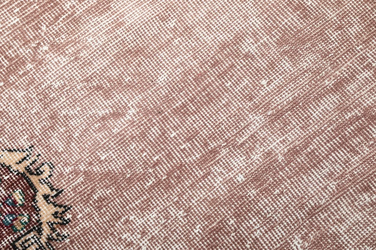 Close-up showing the low pile and distressed texture of the rose wool rug