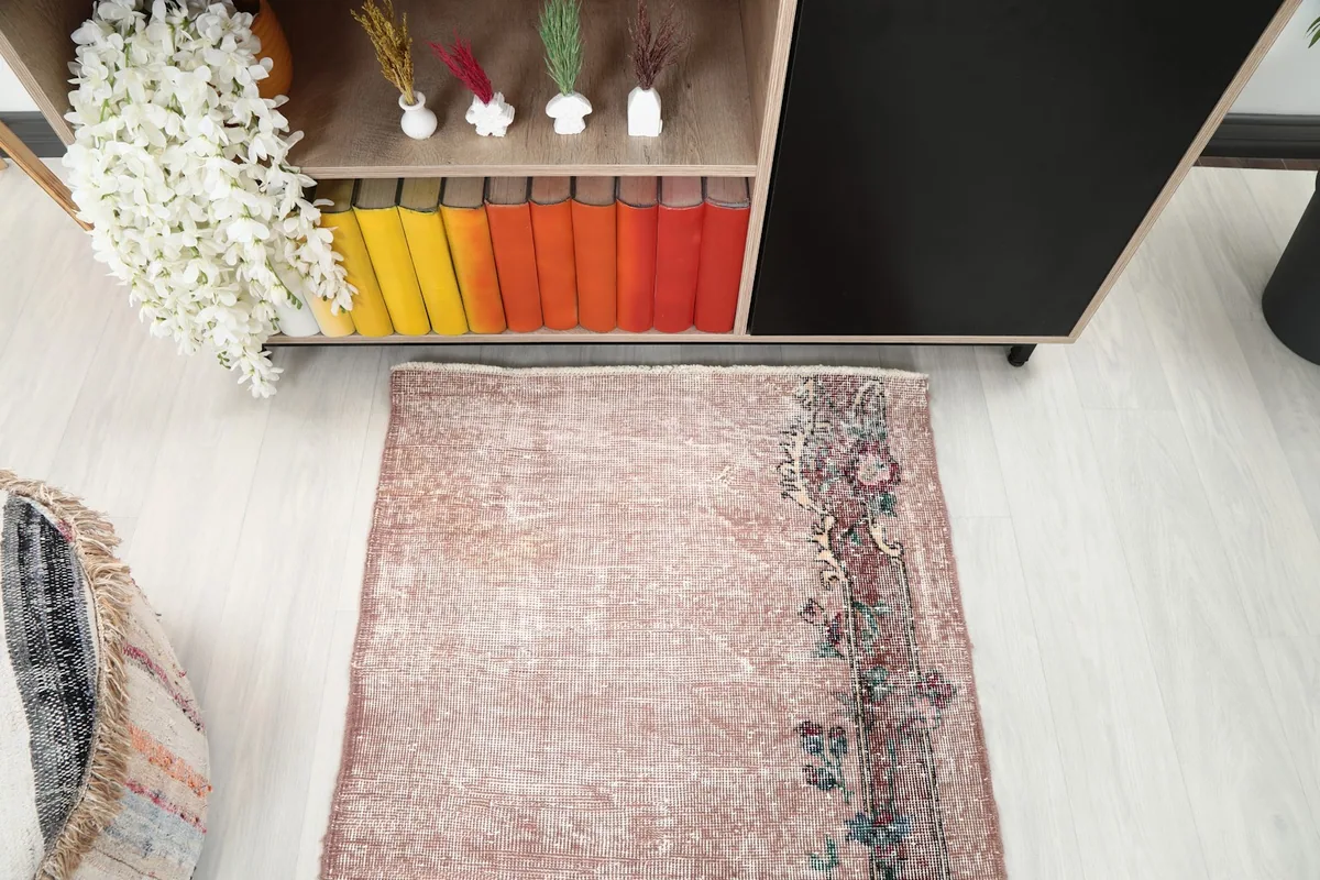 Overhead shot of the rose rug with its distinctive floral border and worn texture