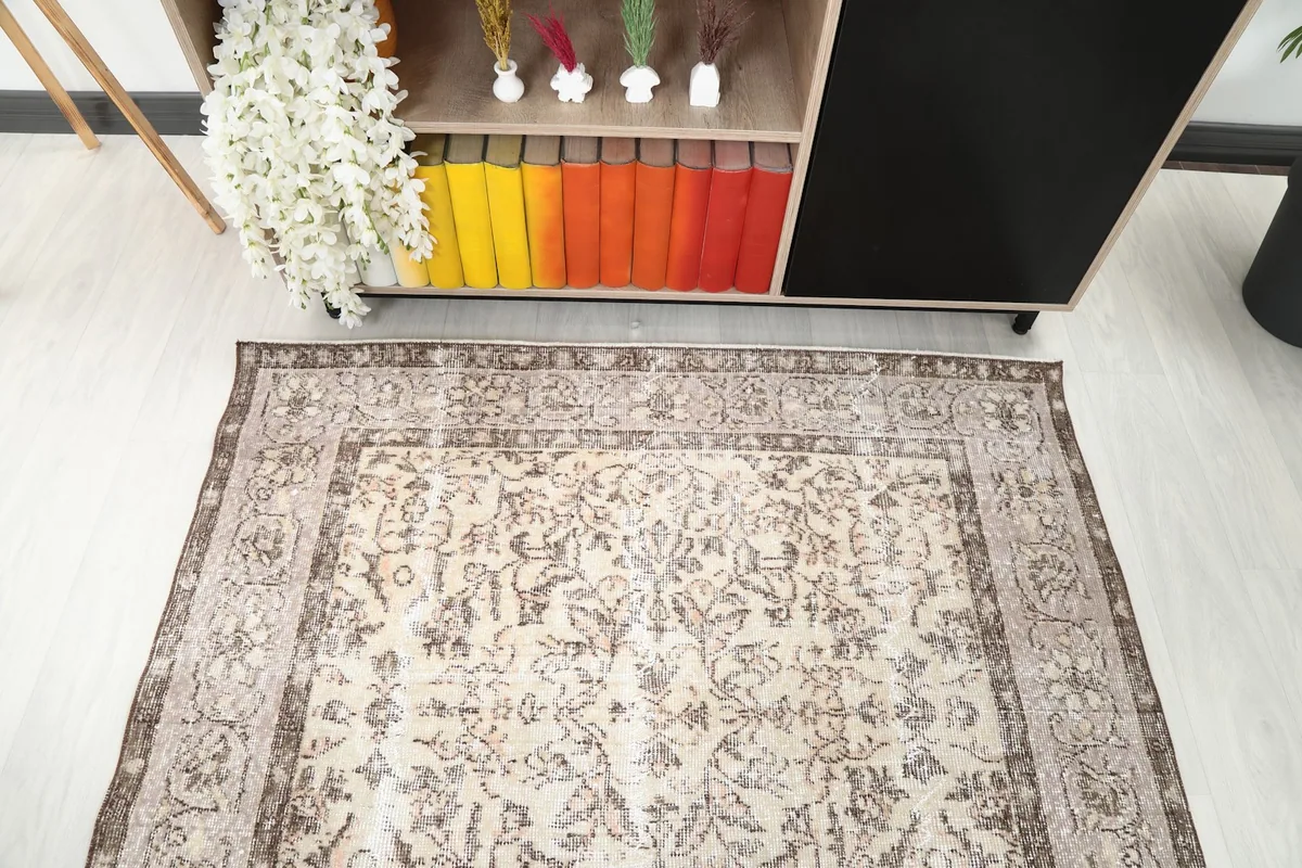 Detail view of the rug's pattern and border in a room setting, near a bookshelf with colorful books.