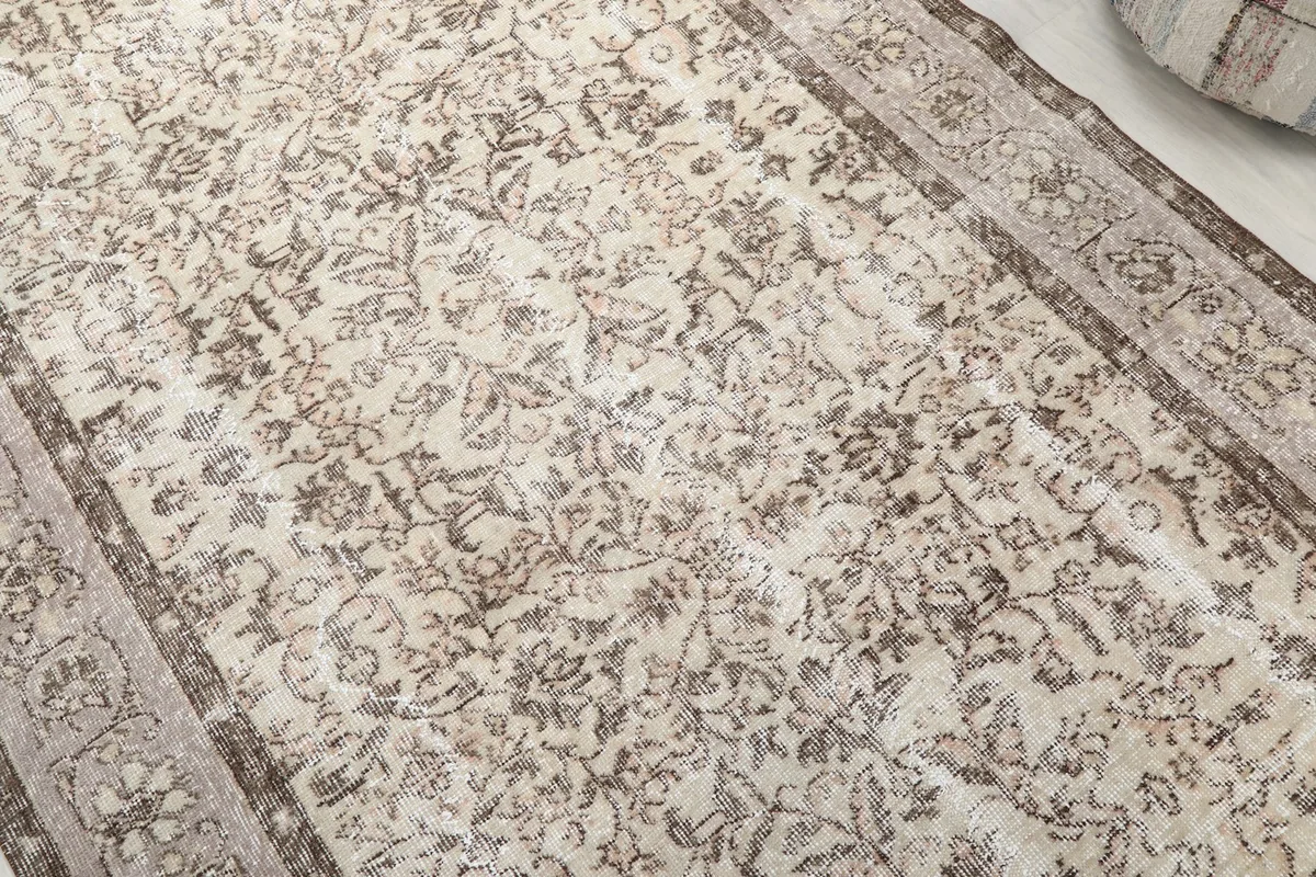 Close-up of the cream field and faded brown floral motifs, showing the rug's texture and wear.