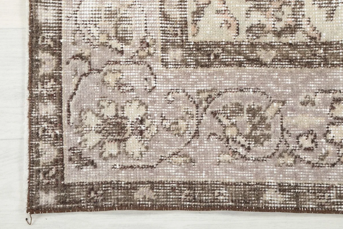 Close-up of the rug's border, showing the gray background and traditional floral patterns.