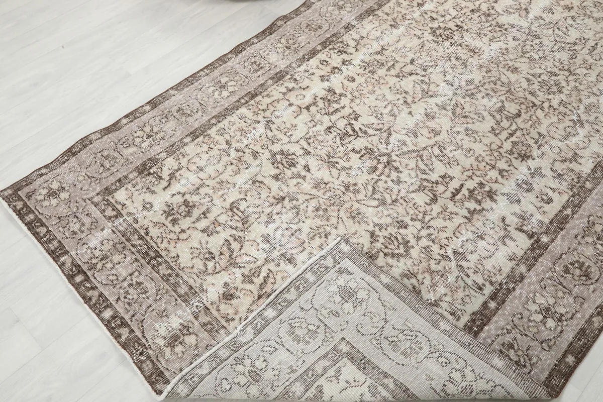Corner of the rug folded back, revealing the reverse side and showing the cotton foundation.