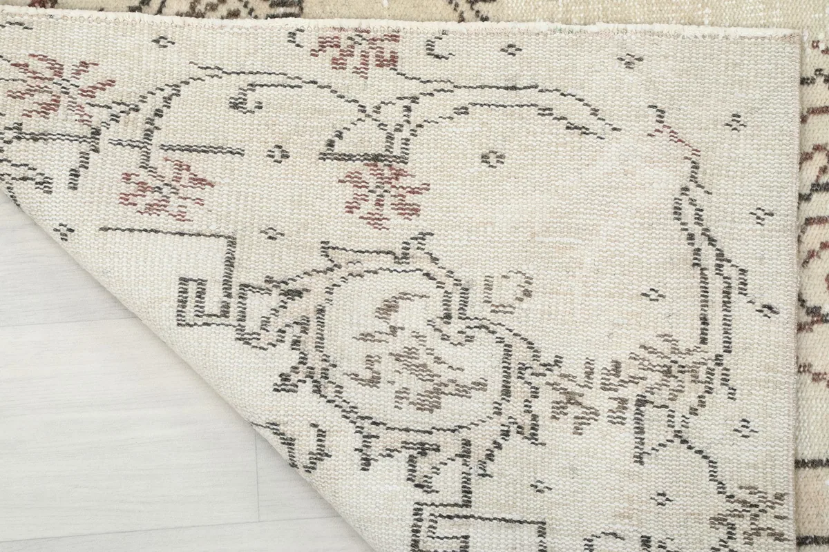 Corner of the rug folded back to show the cotton foundation and hand-knotted construction