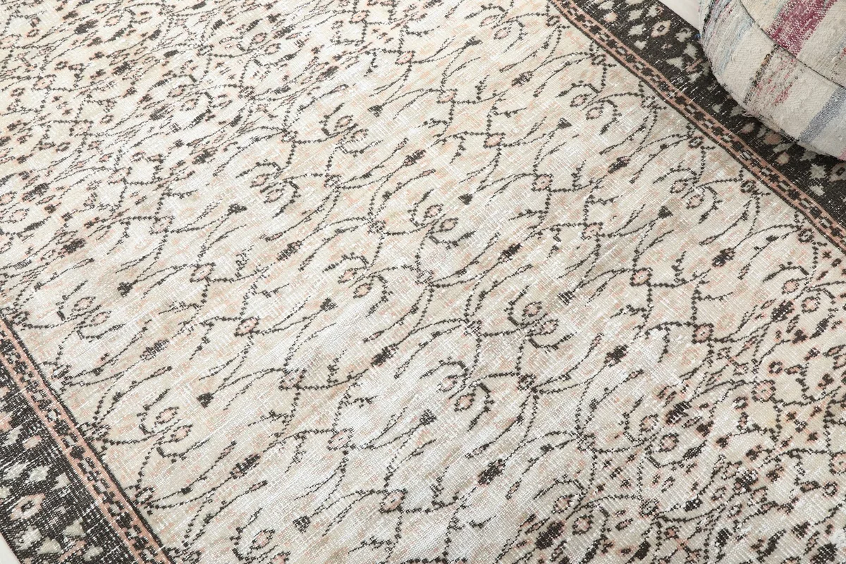 Detailed view of the ivory field with charcoal and rose floral and geometric motifs.