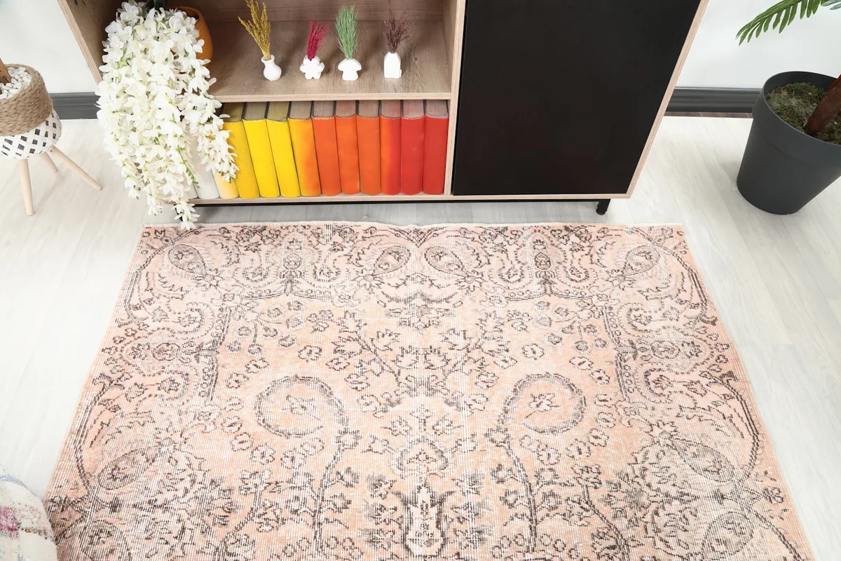 Side angle view of the rug's patterns and colors, extending towards a bookshelf