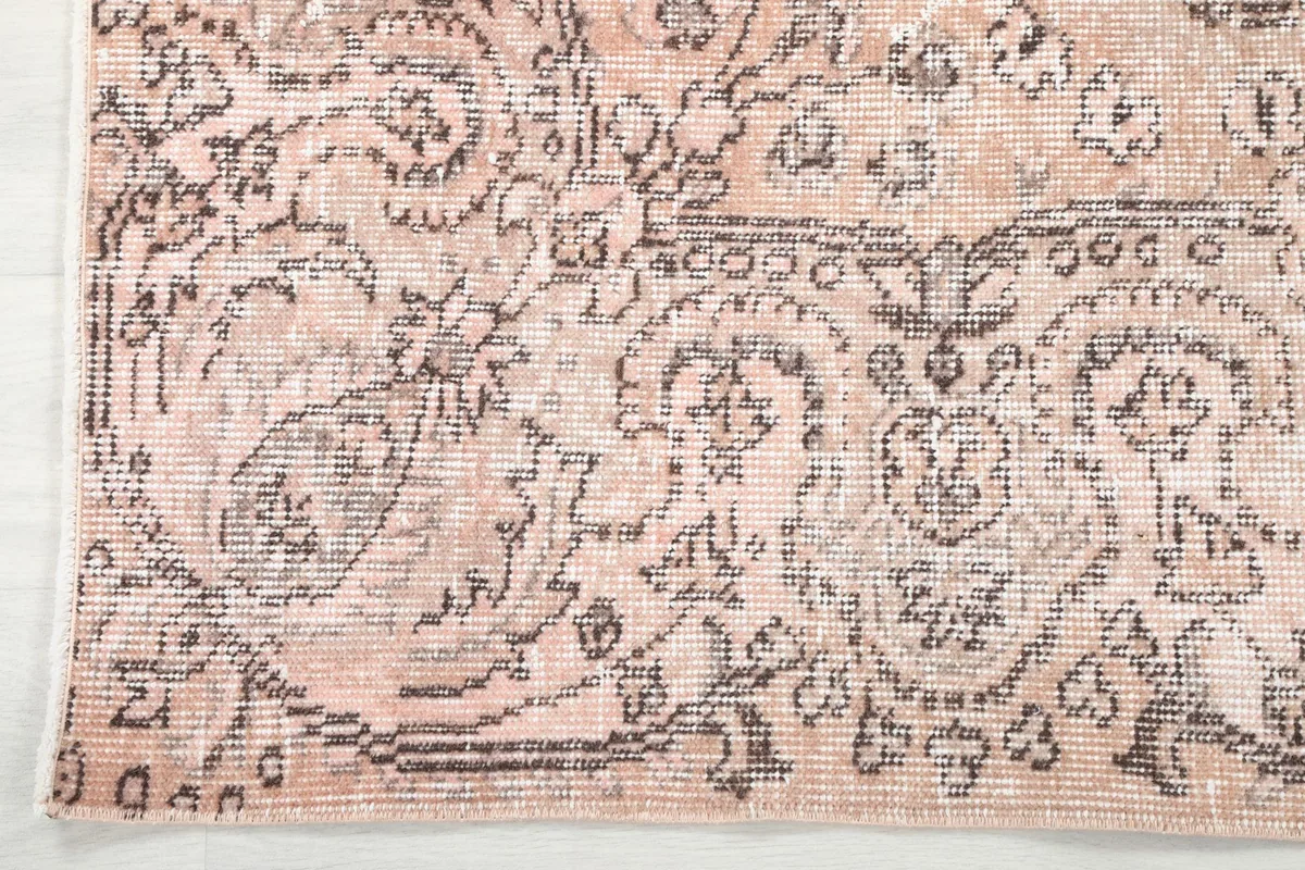 Detailed view of the rug's border design, showing the intricate gray patterns on a rose background