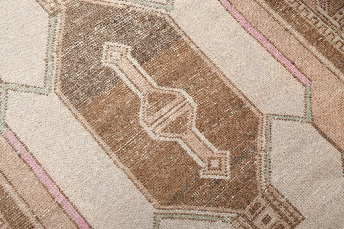 Close-up of the central geometric motif on the rug, revealing the low pile and subtle color shifts