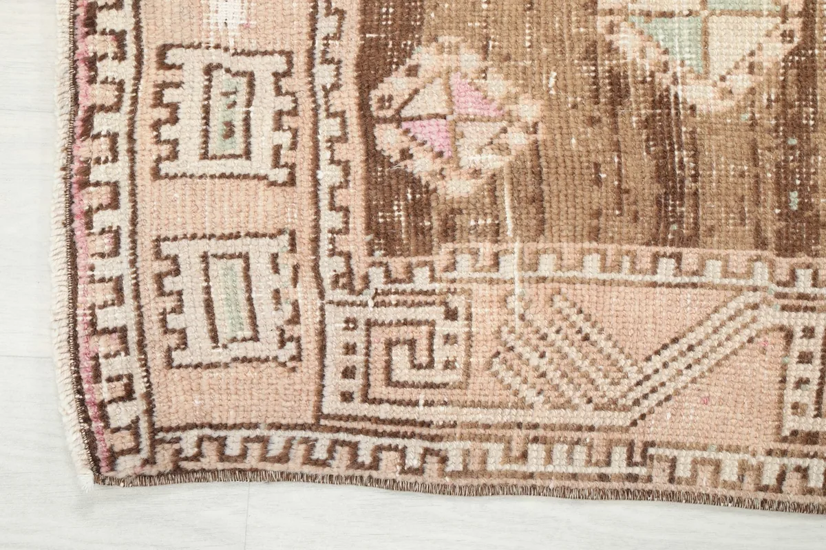 Detail of the rug's border and corner, showcasing the intricate geometric patterns and original fringe
