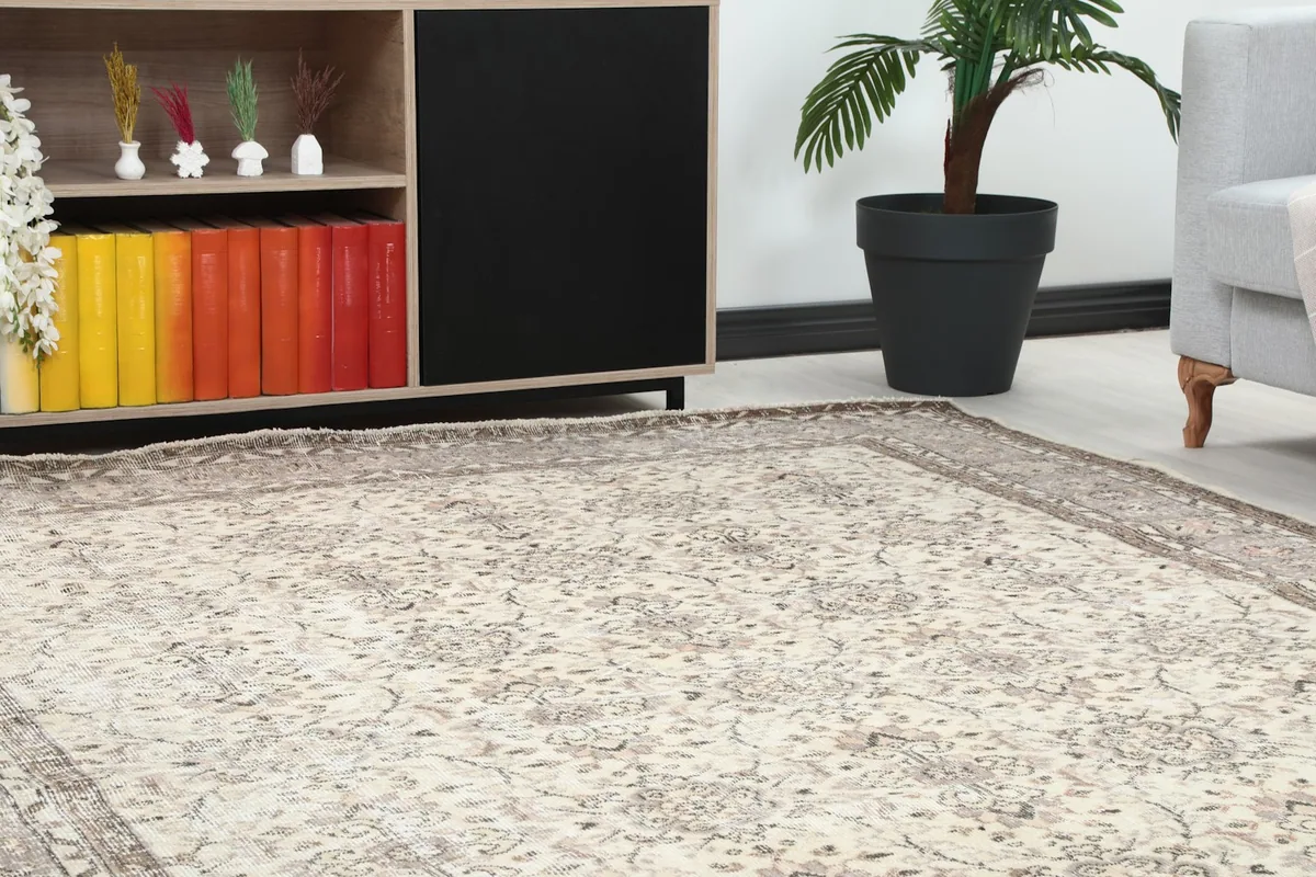 Close-up view of the ivory and gray rug's pattern in a room setting, next to a cabinet and plant.