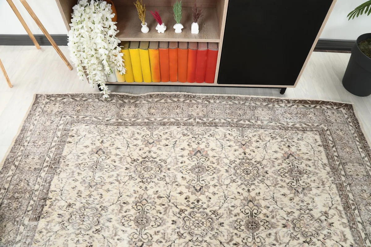 Detail view of the rug's field and border, showing its placement in a room with a bookshelf.