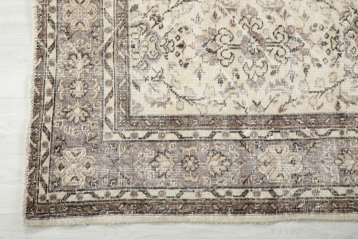 Corner detail of the rug's border design, showcasing the gray and tan geometric patterns.