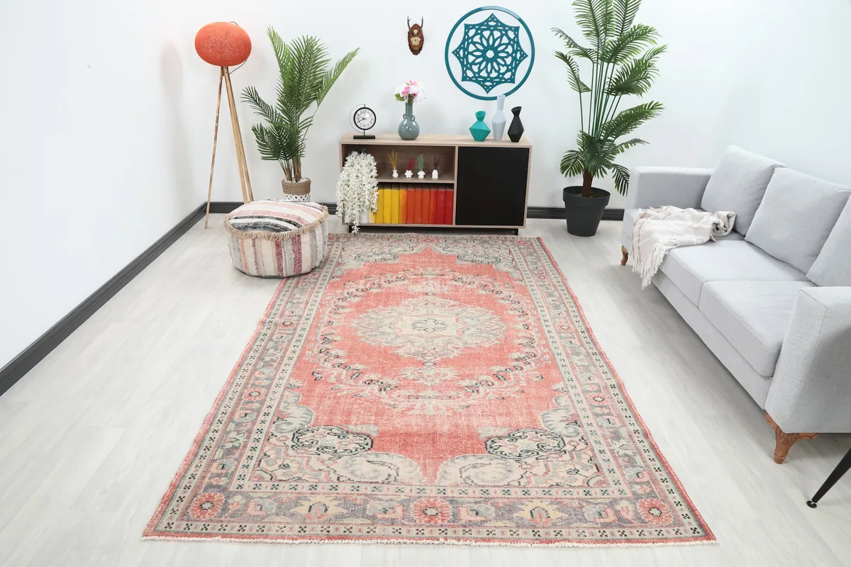 Vintage Anatolian rug displayed in a living room setting with a gray sofa and wooden furniture
