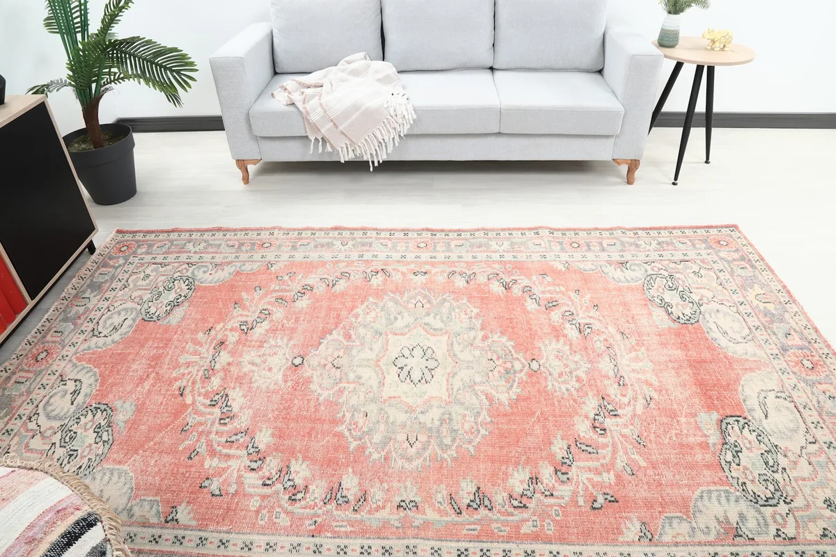 Overhead view of the vintage rose rug in a room, showing its placement in front of a sofa