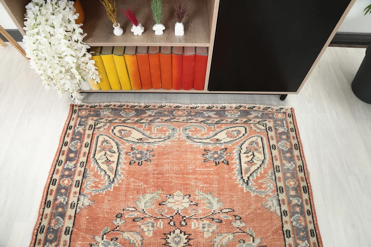 Angled view focusing on the upper portion of the rug, showing details of the faded rust and blue tones.