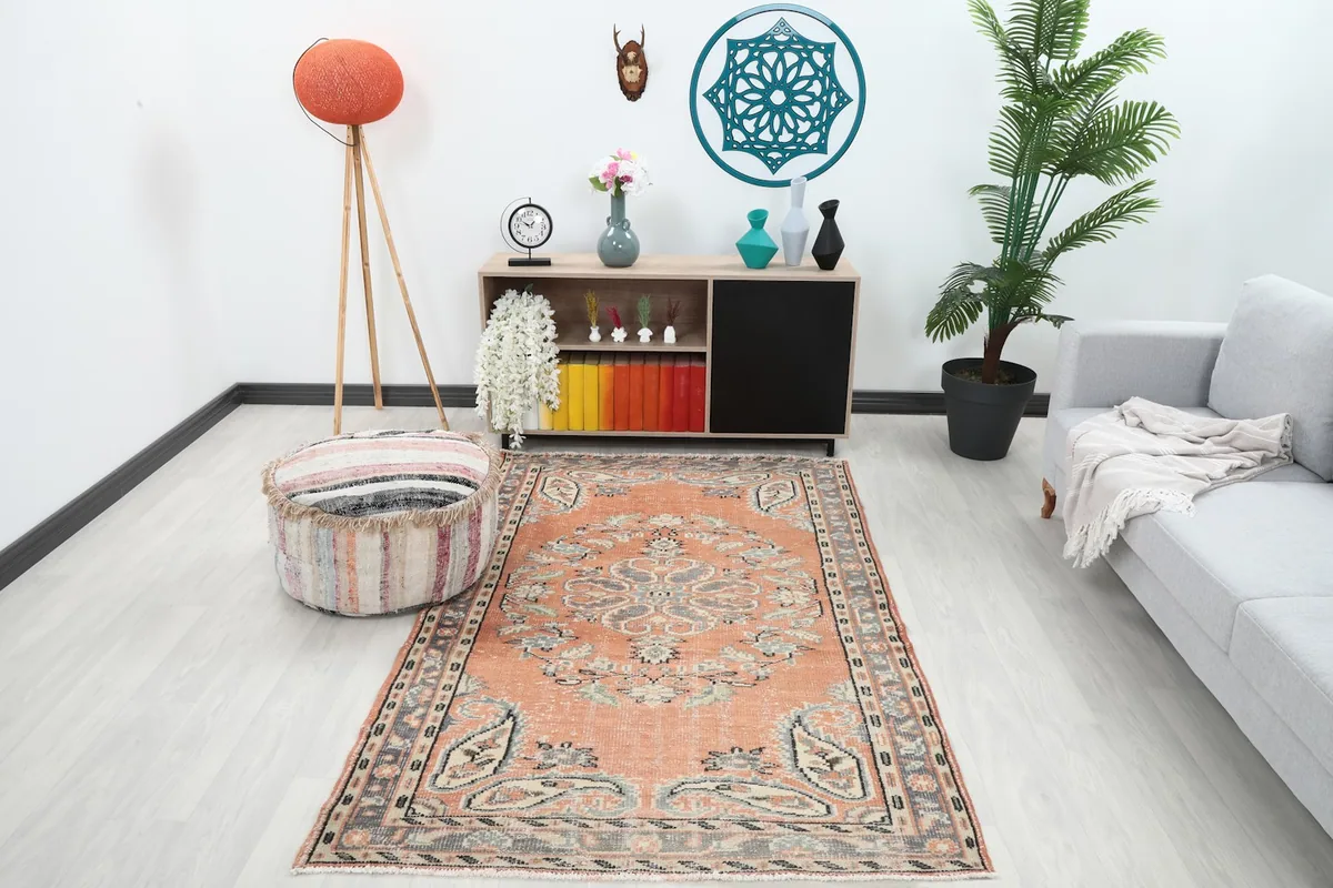 Vintage rust rug displayed in a modern living room setting with a gray sofa and wooden furniture.