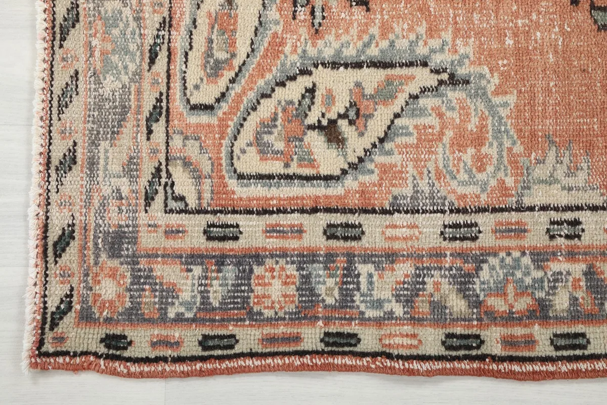 Corner detail of the rug, illustrating the intricate gray and cream border patterns.