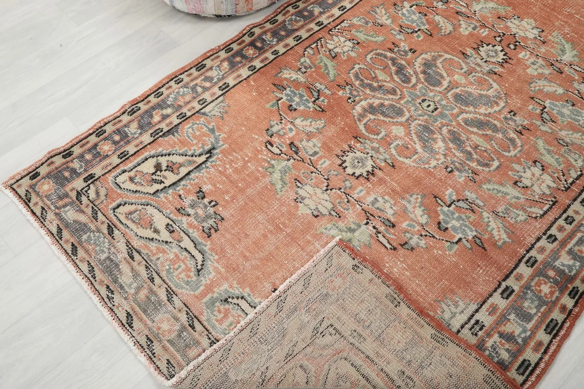 View of the rug with a corner folded back, revealing the reverse side and knotting.