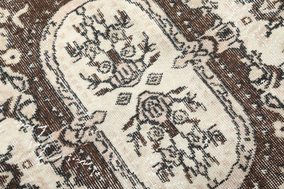 Macro detail of the medallion's intricate weaving and the subtle color shifts in the vintage wool.