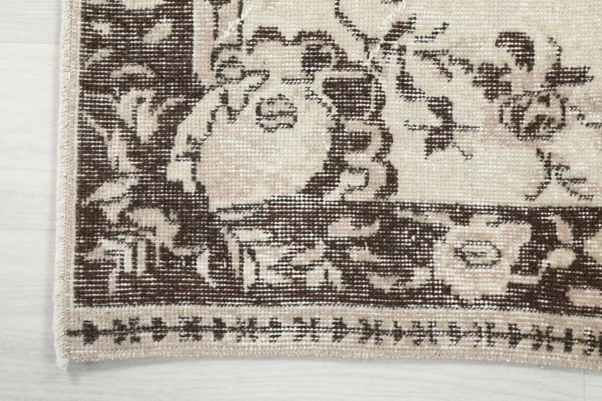Corner detail showing the rug's outer border and the edge of the ivory field, revealing minor wear.