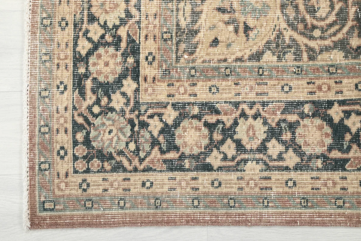 Detailed image of the Faded Rust Medallion Anatolian Rug's corner, showcasing the ornate navy and beige border.