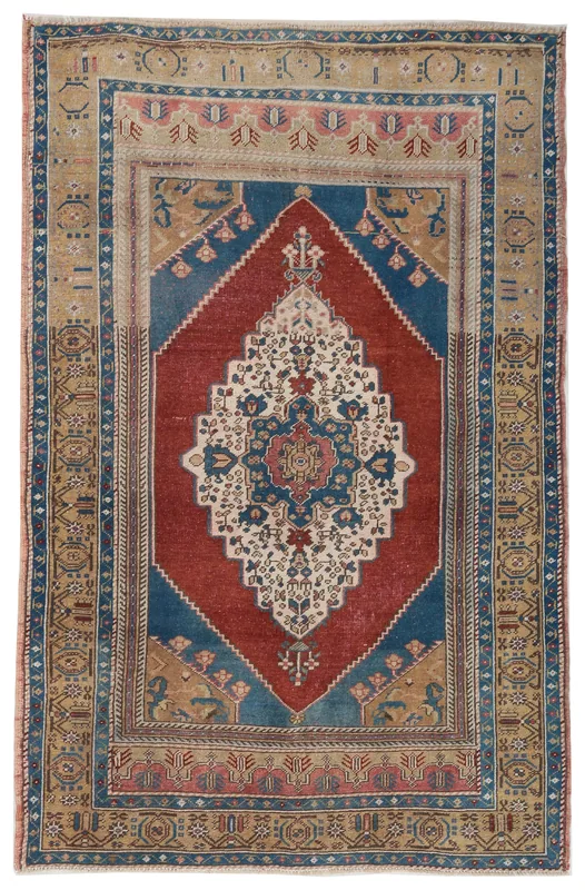 Overhead view of a vintage Anatolian rug with a red field, blue medallion, and beige border