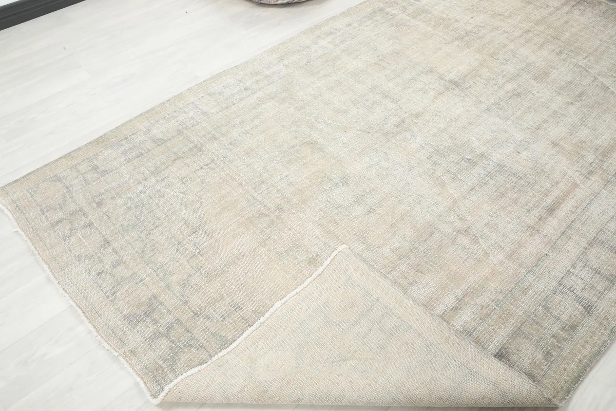 Corner of the Anatolian rug folded back, revealing the hand-knotted construction and cotton foundation