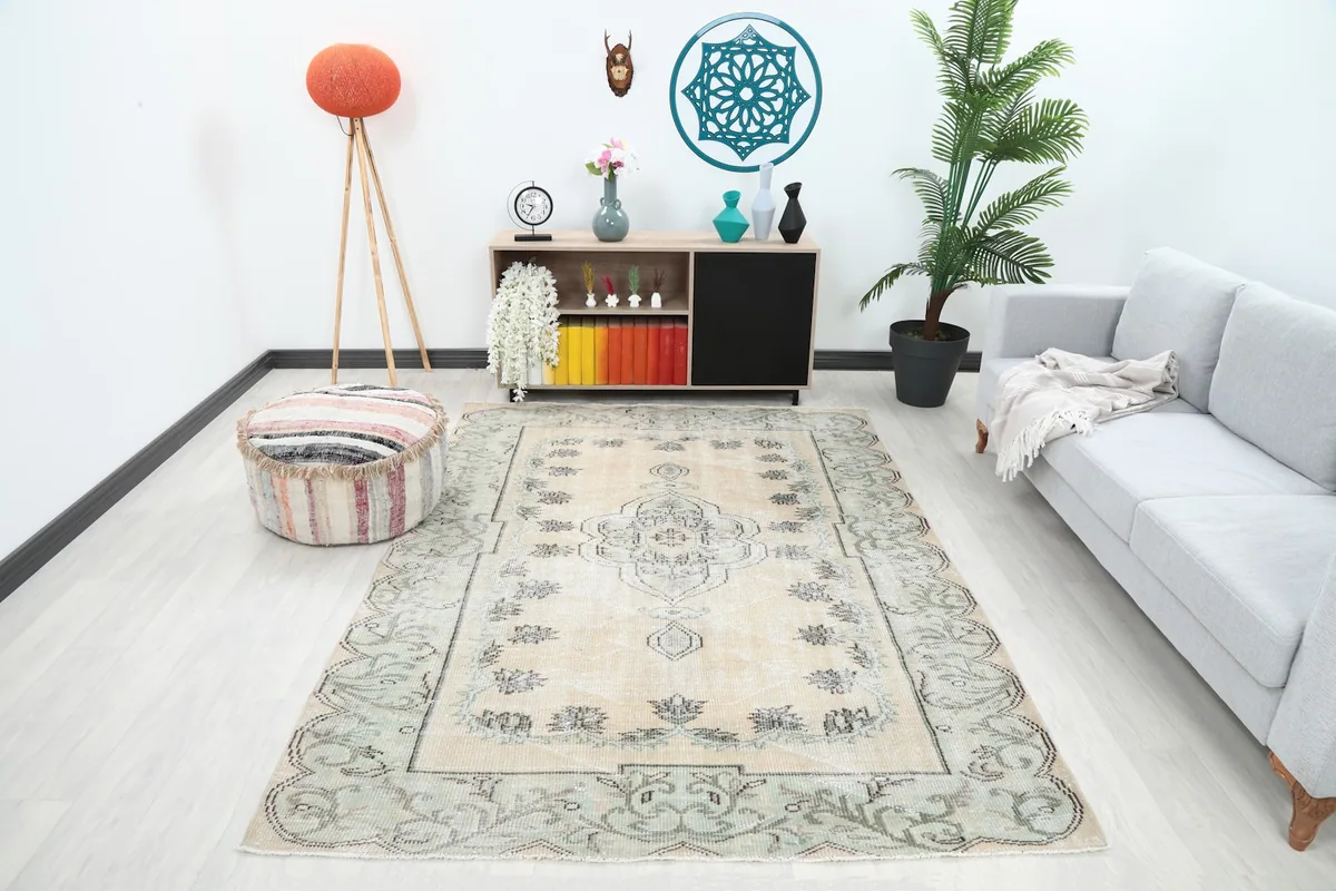 The beige and green vintage rug laid out in a modern living room setting.