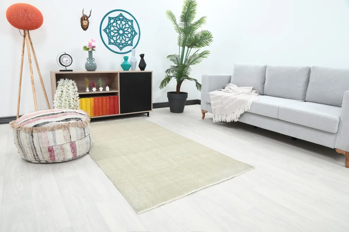 Angled view of the cream distressed rug in a living room, showing its placement relative to a couch.