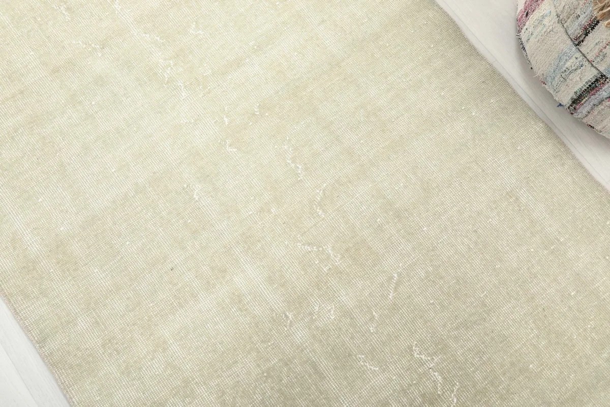Detailed close-up of the cream wool pile, showing the subtle distressed texture and variations.