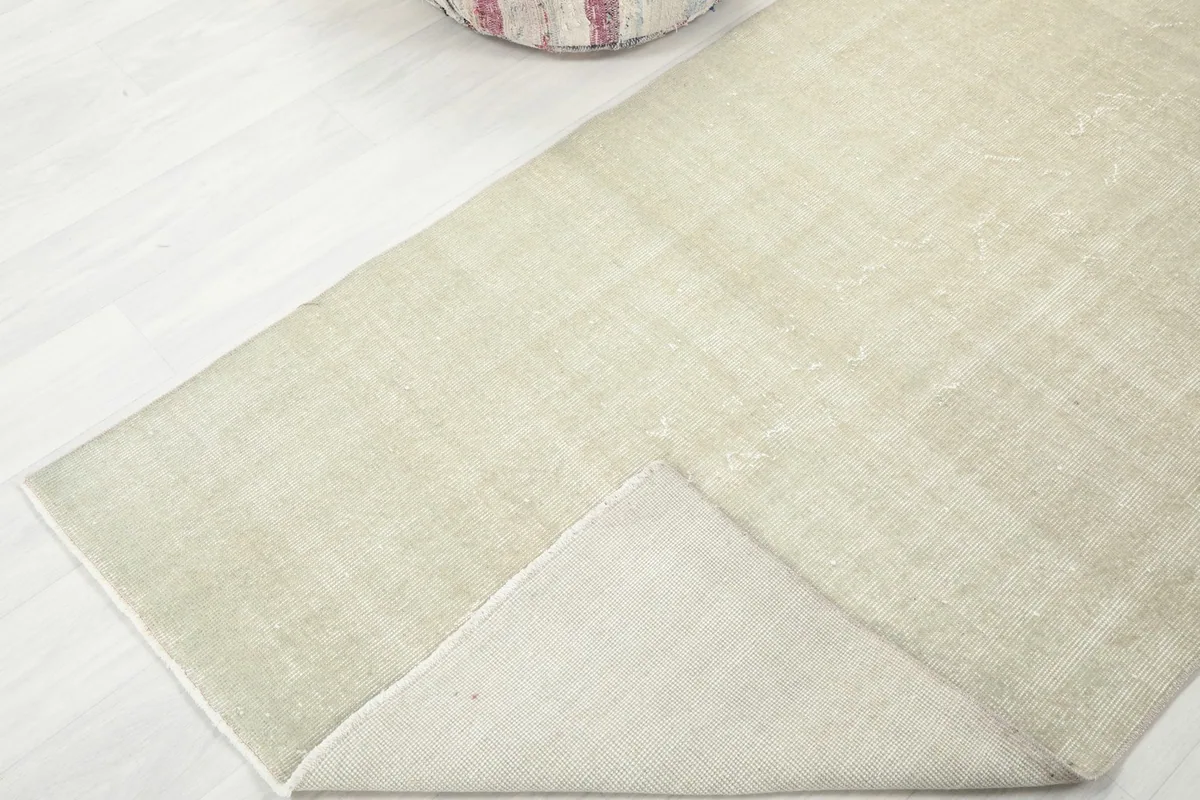 Corner of the rug folded back to reveal the cotton foundation and hand-knotted construction from the underside.