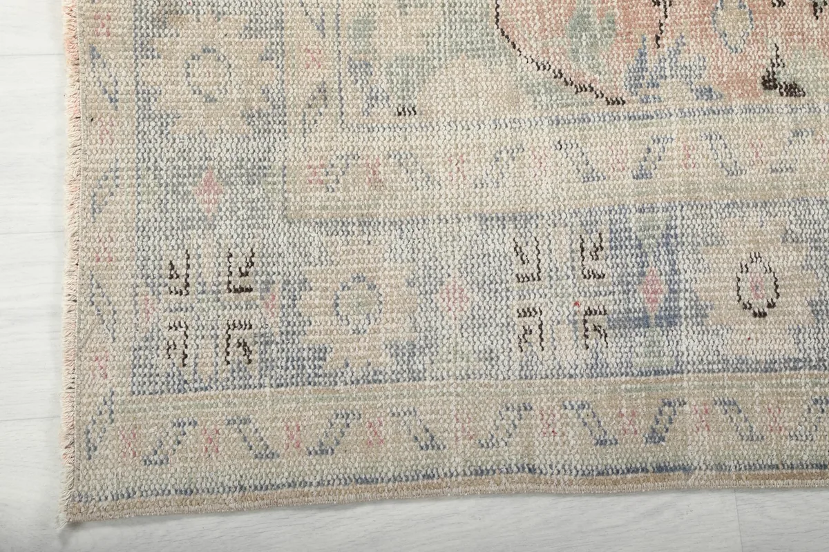 Close-up of the rug's blue border with geometric patterns and subtle rose accents
