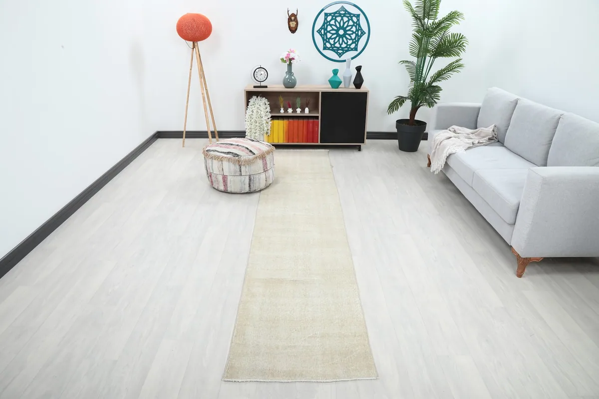 Cream vintage runner rug laid out in a modern living space with light flooring, showing its full length.