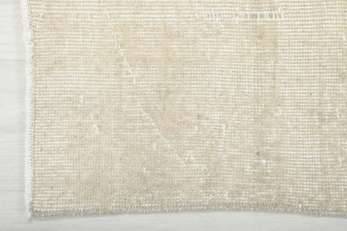 Close-up of the rug's edge, showing the hand-knotted construction and the cotton foundation beneath the wool pile.