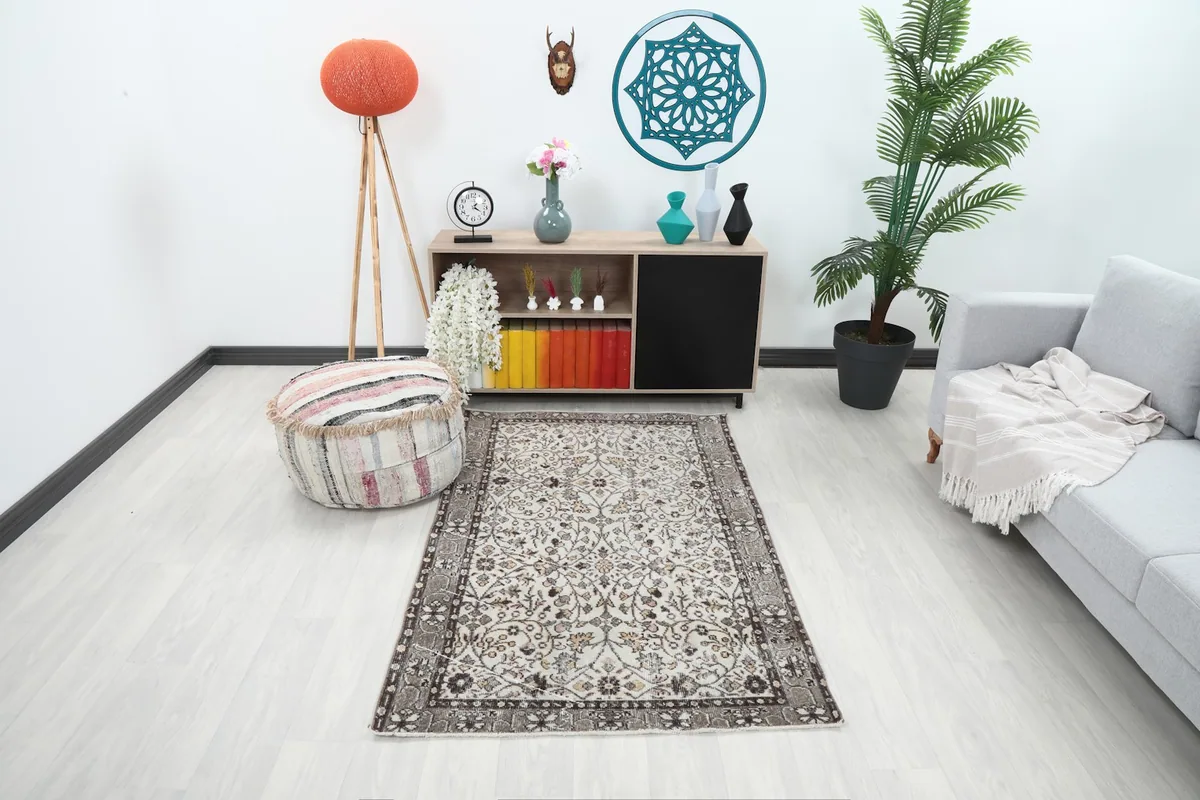 Vintage cream and brown rug in a living room setting with a sofa and pouf
