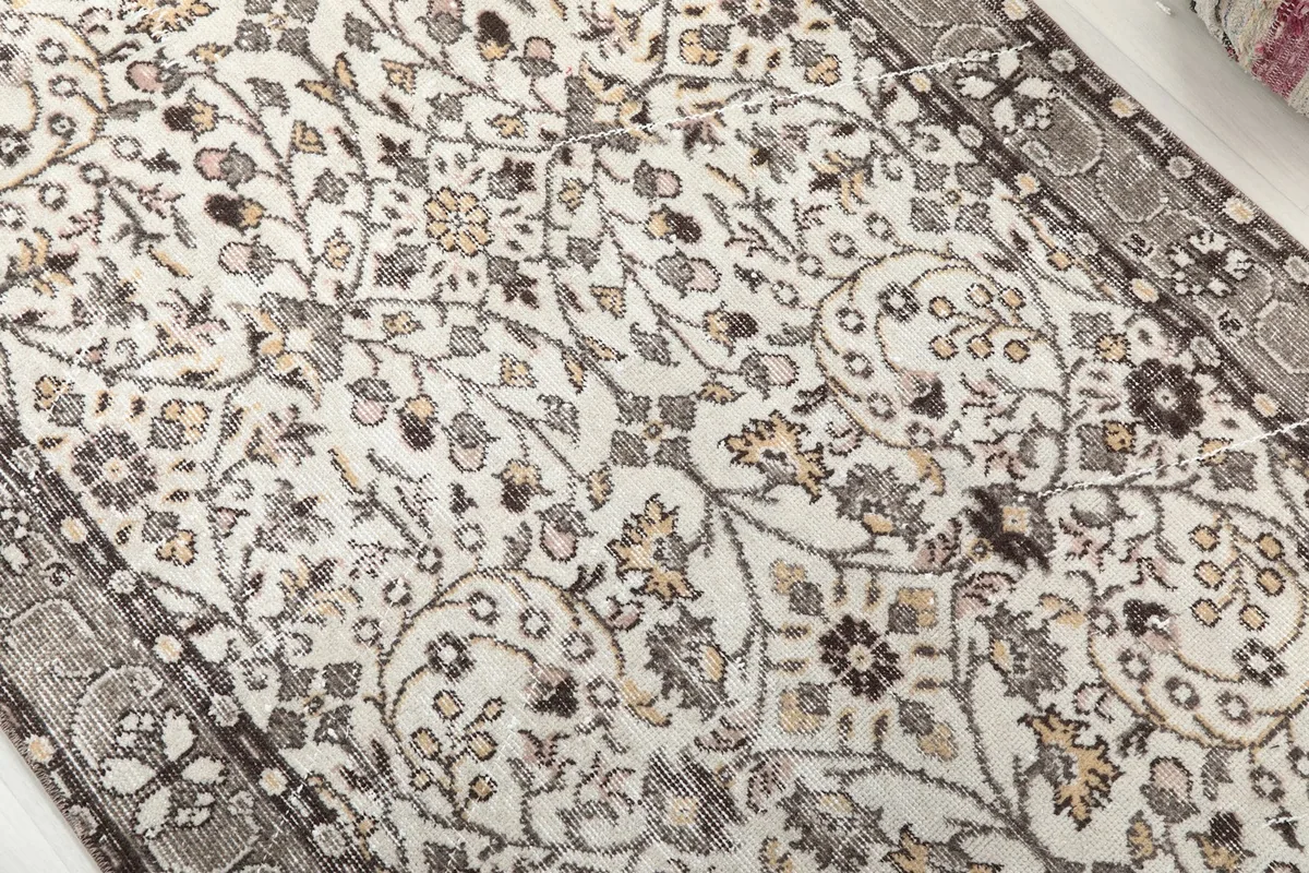 Close-up detail of the rug's cream field with intricate floral and vine motifs