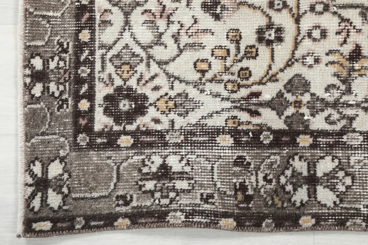 Close-up of the rug's decorative brown and gray border and corner design