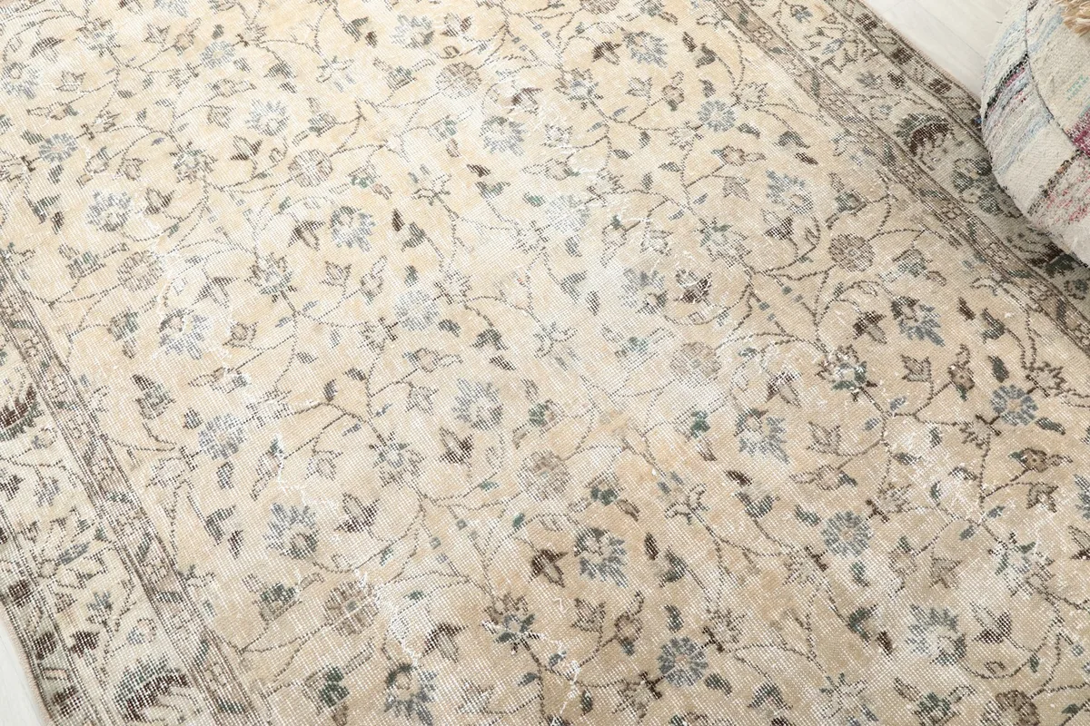 Close-up of the rug's main field, showing the intricate floral vine pattern and gentle patina