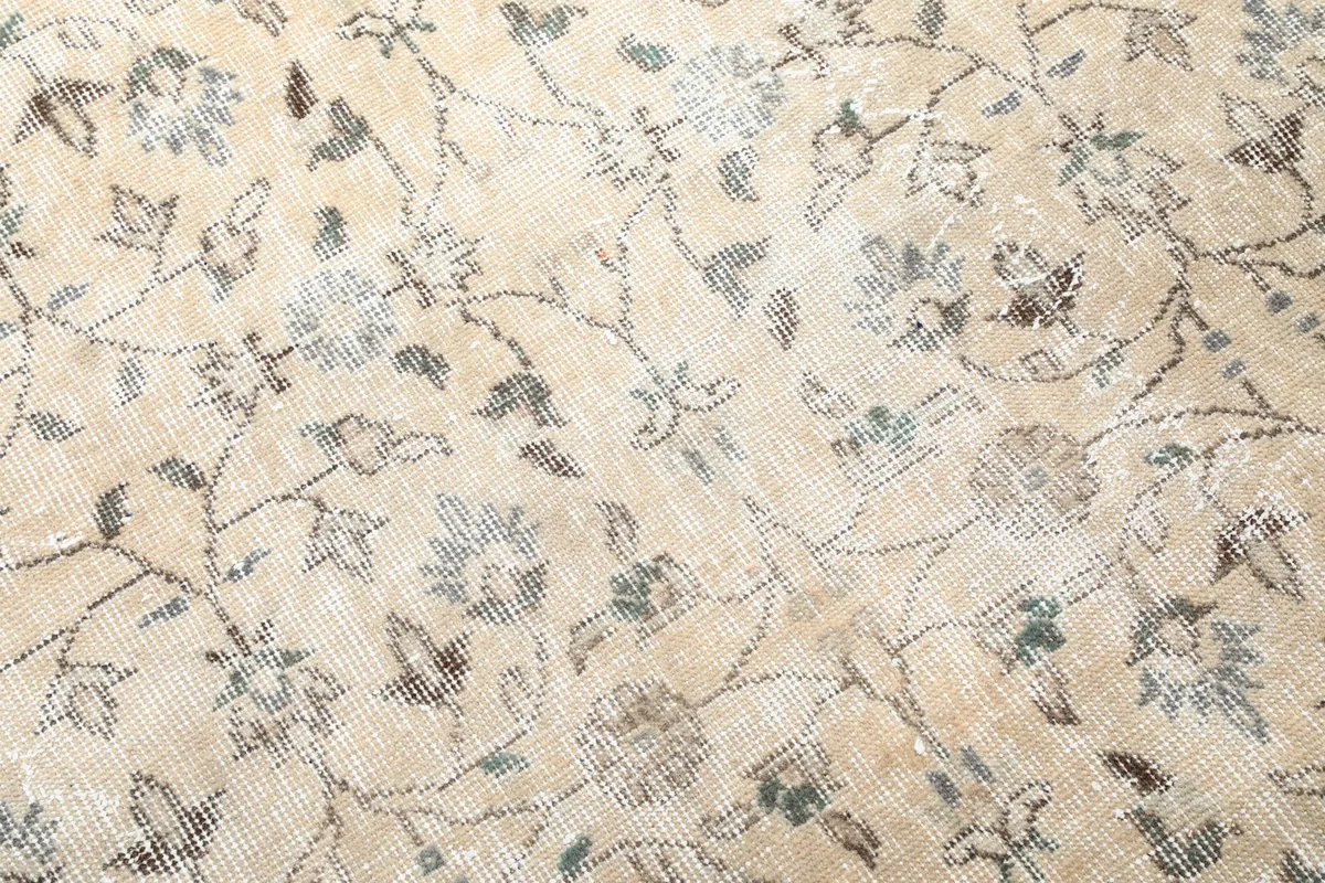 Detailed view of the hand-knotted wool pile, revealing muted olive and gray tones in the motifs